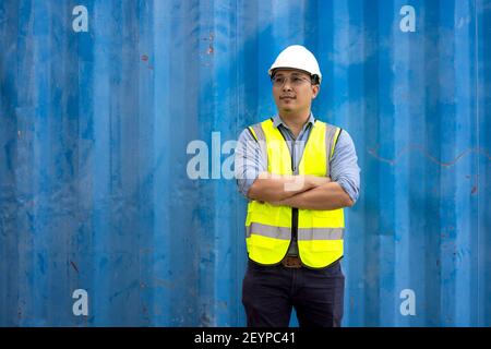 Portrait of engineering man wearing uniform safety suit and helmet in industrial containers. Stock Photo