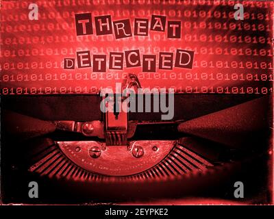 Threat Detected typed into a Vintage Typewriter with a computer screen with a Binary Code Red background Stock Photo