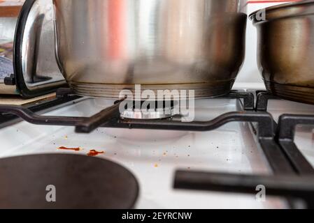 A stainless steel pot and frying pan standing on a switched off gas stove in the kitchen. Stock Photo