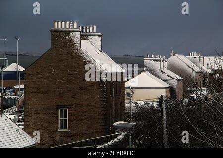 Traditional buildings rooftops covered with snow and dark blue sky in background on winter day on scottish island in northern Scotland Stock Photo