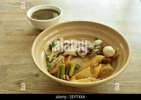 dry large rice noodles topping slice braised and fermenting with meatball dressing black sweet soy sauce on bowl eat couple brown herb soup Stock Photo