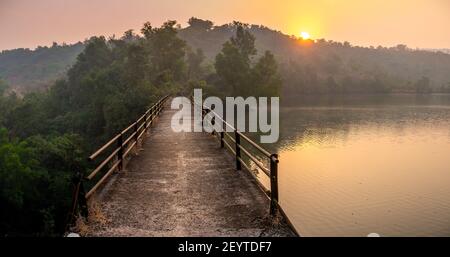 Local dam bridge surrounded by trees at sunrise Stock Photo