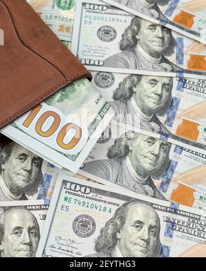 Men's wallet with money. Close up of leather wallet with american dollar banknotes on one hundred dollar bills. Vertical shot Stock Photo