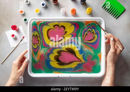 woman drawing with paints floral pattern on water Stock Photo