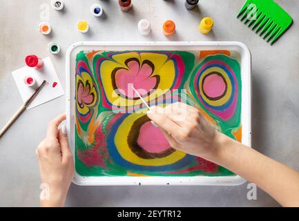 woman drawing with paints floral pattern on water Stock Photo