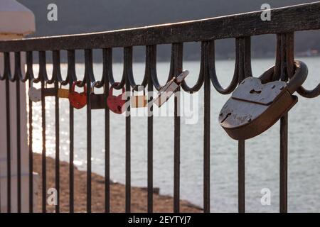 Padlocks on the railing of the bridge as a symbol of love. Selective focus on a large black barn castle. Stock Photo
