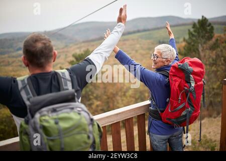 Happy hikers couple with raise arms looking landscape Stock Photo