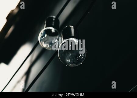 Two light bulbs on black background. Concept photo of bulbs. Hanging bulbs on the wire. Moody background. Stock Photo