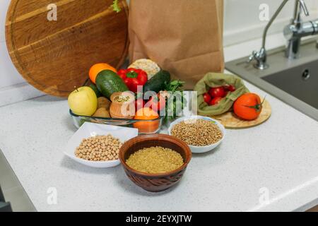 World Vegan Day. Different raw vegetables, herbs and cereals on the kitchen table. . Fresh raw food seasonal vegetables on home kitchen. Vegetarian Stock Photo