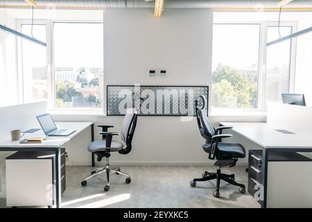 Empty office space while officer is working from home to avoid corona virus. Open space office in loft style in new normal. Working In An Empty Office Stock Photo