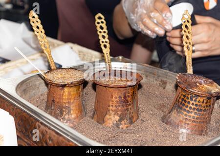 Aromatic coffee brewed in hot sand - turkish coffee brewing in cezve. Stock Photo