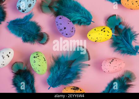 Colored easter eggs and blue feather on a pink background Stock Photo