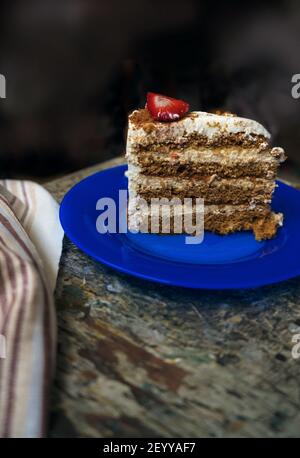 vertical image of piece of birthday cake decorated with fresh strawberry lying on blue glass plate Stock Photo