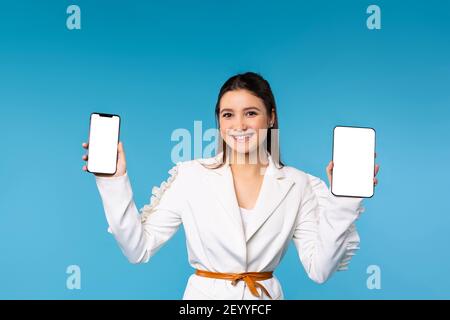 Close up view of young businesswoman showing both hands, holding mock up smartphone and digital tablet screen while working on her project. Successful Stock Photo