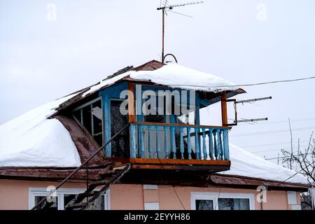 Bashkiria, Russia - 01.30.2021: Old decrepit open balcony in the Russian village. Superstructure on the house. Blurry winter skies all around. Stock Photo