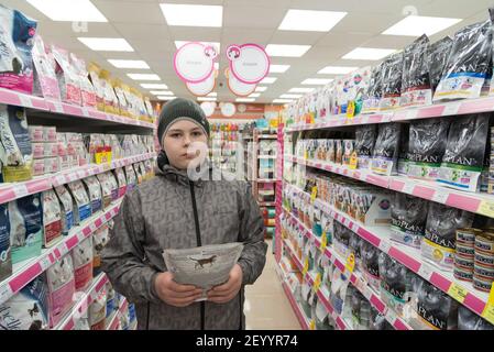 Moscow, Russia - April 16.2016. Teen boy chooses dry food for cats in Four paws pet store Stock Photo