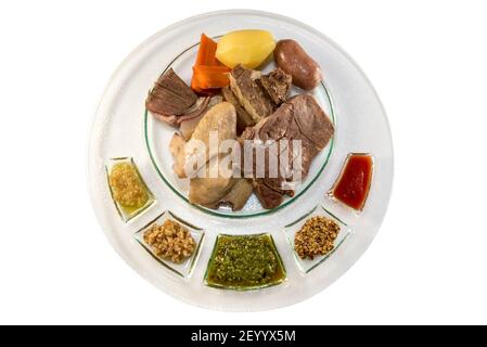 mixed boiled meat, typical Piedmontese Italian dish with sausage, beef and chicken and sauces in plate isolateed on white in top view Stock Photo