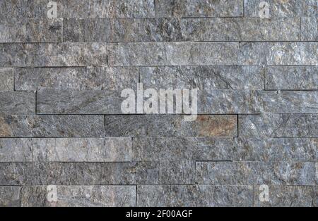 The texture of the natural stone cut in the shape of the tiles on the wall Stock Photo