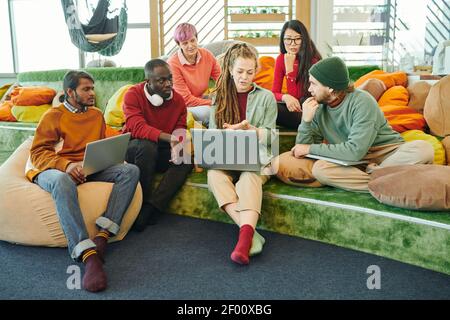Young intercultural managers listening to creative businesswoman explaining points of new project during presentation at start-up meeting Stock Photo