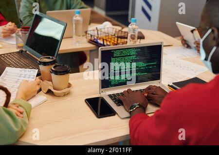 Hands of young contemporary software developer of African ethnicity touching keys of laptop keypad while working over new program Stock Photo