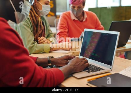 Hands of young it engineer of African ethnicity touching keys of laptop keypad while working over new program or software by workplace Stock Photo