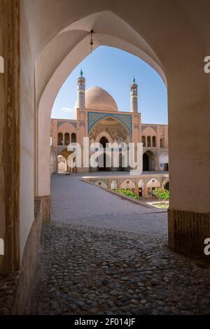 Kashan,Iran-04.08.2019: Courtyard, dome and minarets of Agha Bozorg Mosque in Kashan. Small garden in the middle of the courtyard. Stock Photo