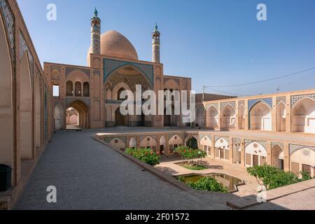 Kashan,Iran-04.08.2019: Courtyard, dome and minarets of Agha Bozorg Mosque in Kashan. Small garden in the middle of the courtyard. Stock Photo