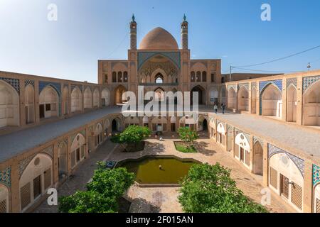 Kashan,Iran-04.08.2019: Courtyard, dome and minarets of Agha Bozorg Mosque in Kashan. Small garden in the middle of the courtyard. Stock Photo