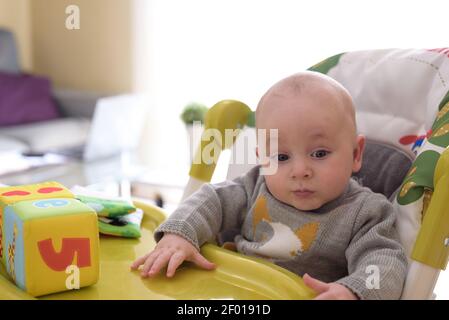 baby playing with his toys while his mother telework from the sofa at home. family conciliation concept. Stock Photo