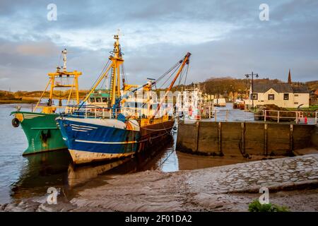 Fishing trawlers moored at Kirkcudbright harbour on the River Dee at sunset in winter, Dumfries and Galloway, Scotland Stock Photo