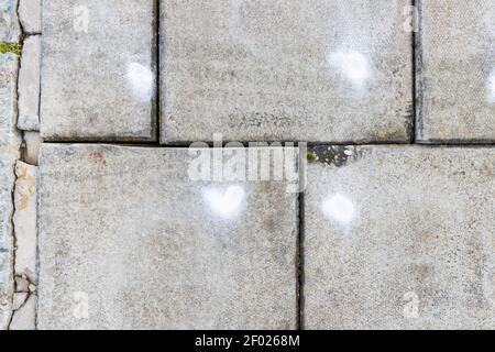 A grey concrete pavement slab with a white spray paint on it, with abstract markings and theme. Stock Photo