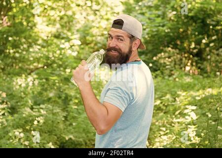 Hydrate Or Die. brutal hipster in forest. discover new places. time for picnic. guy drink water. mature bearded man in cap. summer camping vacation. man hipster hiking. male feel thirsty. Stock Photo