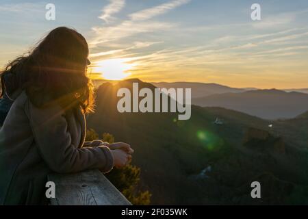 A shallow focus shot of a female leaning on a wooden fence enjoying the beautiful view in  Las Médulas, Spain Stock Photo