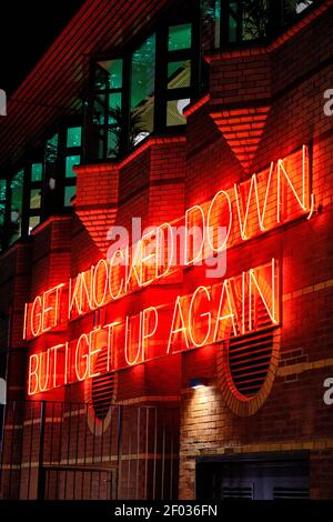 A vertical shot of an inspirational sentence in red neon lights on a brick wall Stock Photo
