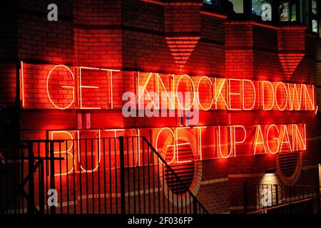 An inspirational sentence in red neon lights on a brick wall Stock Photo