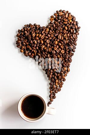 A moment for a lovely break. A coffee beans heart flying from a cup on a white background. Stock Photo