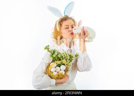 Beautiful young woman kissing white rabbit. Cute girl on Easter day. Hunts for Easter eggs. Stock Photo