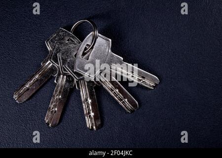 Keys to the front door. Metal security systems for single-family houses. Dark background. Stock Photo