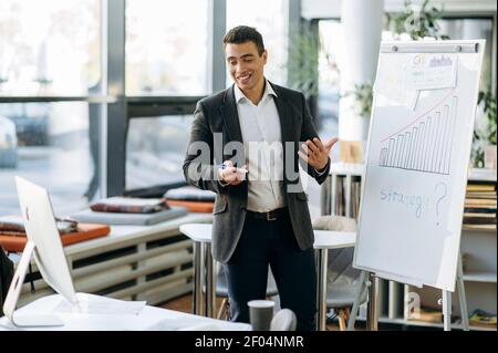 Friendly successful male manager making presentation, submit report by video conference. Confident business man at online briefing with colleagues, discussing the project, distant office work concept Stock Photo