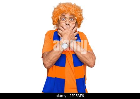 Senior hispanic man football hooligan cheering game shocked covering mouth with hands for mistake. secret concept. Stock Photo