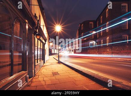 Illuminated High Street of Harrow on the Hill with a passing bus and cars in motion, Greater London, England Stock Photo