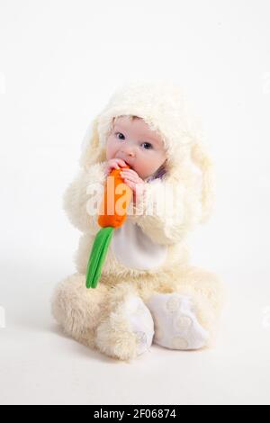 Portrait of a cute baby dressed in Easter bunny ears with a carrot Stock Photo