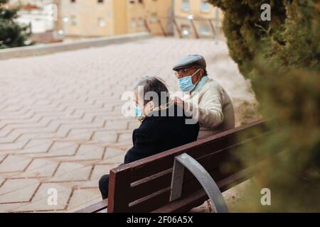 Back view of an unrecognizable elderly couple sitting on a park bench Stock Photo