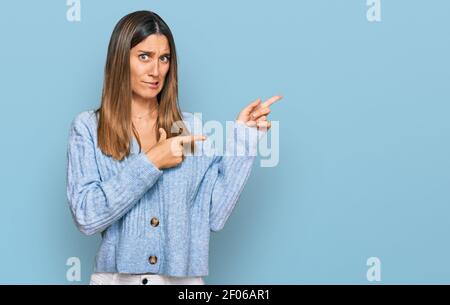 Young woman wearing casual clothes pointing aside worried and nervous with both hands, concerned and surprised expression Stock Photo
