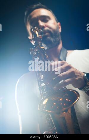Male musician in classy outfit playing alto saxophone during jazz concert Stock Photo
