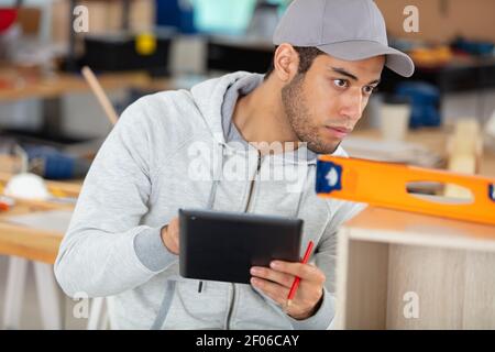 handsome carpenter is using a digital tablet in the workshop Stock Photo
