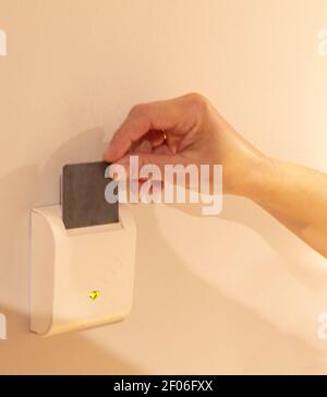 selective one-handed focus by inserting the hotel room card into an electronic device to turn on the light of your entire room Stock Photo