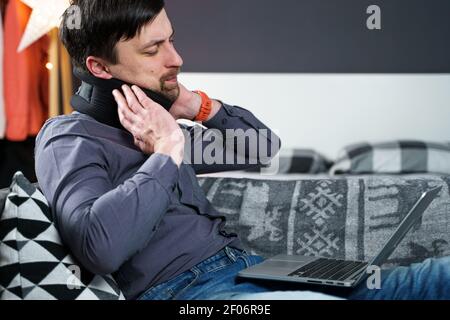 Business man overtime work massaging his neck while suffering from pain, uses a neck collar to relieve muscle tension. Man with health problems Stock Photo