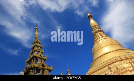 Two golden temples with cloudy blue sky within Shwedagon Pagoda complex in Yangoon Myanmar (Burma) Stock Photo