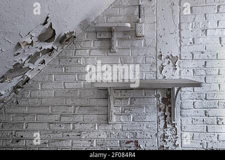 Peeling white paint on brick wall with shelf, interior of dilapidated old building, Philadelphia Pennsylvania USA